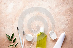 Flat lay composition of toothbrushes, toothpaste and mouthwash on a beige background with space for text