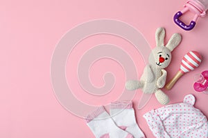 Flat lay composition with toy bunny and child`s clothes on background, space for text
