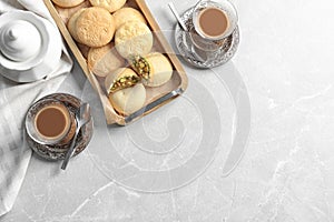 Flat lay composition with tray of cookies for Islamic holidays, cups and space for text on table.