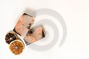 Flat lay composition with two handmade soaps of brown-pink color with an orange tint and dried slices of oranges on a
