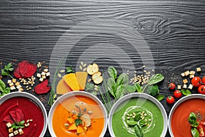 Flat lay composition with various soups, ingredients and space for text on wooden background