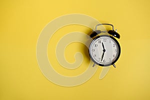 Flat lay composition with a vintage alarm clock on yellow background with copy space to add text. Back to School and Teachers Day