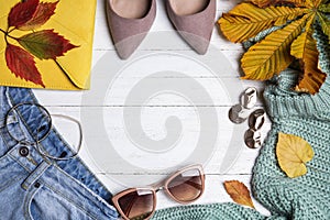 Flat lay composition with warm clothes and autumn leaves on white wooden background