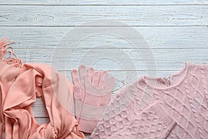 Flat lay composition with warm clothes on wooden background. Space for text