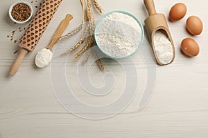 Flat lay composition with wheat flour and eggs on white wooden table. Space for text
