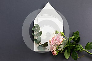Flat lay composition with a white envelope, blank card and a peony rose flower on a grey background.