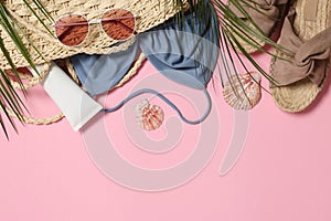 Flat lay composition with wicker bag and other beach accessories on pink background. Space for text