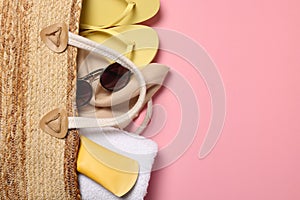 Flat lay composition with wicker bag and other beach accessories on pink background. Space for text