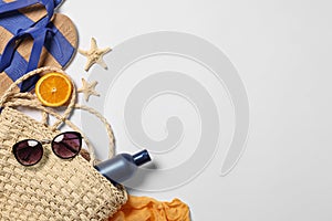 Flat lay composition with wicker bag and other beach accessories on white background. Space for text
