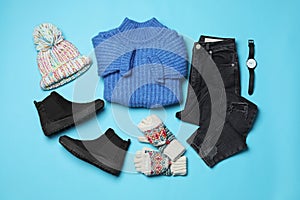 Flat lay composition with winter clothes and boots on blue background