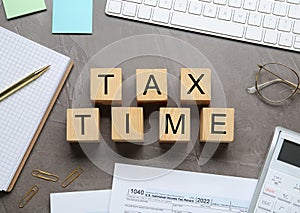 Flat lay composition of wooden cubes with words Tax Time and documents on table