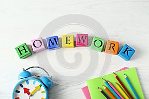 Flat lay composition with word HOMEWORK made of black cubes on wooden table