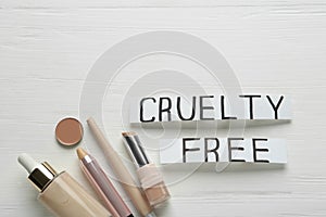 Flat lay composition with words Cruelty Free and cosmetic products not tested on animals against white wooden background