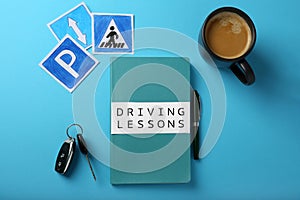 Flat lay composition with workbook for driving lessons on light blue background. Passing license exam