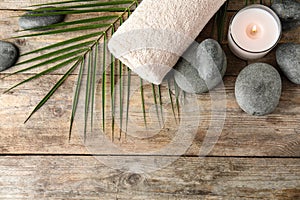 Flat lay composition with zen stones, towel and candle on wooden background