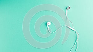 Flat lay concept: headphone on Mint backgrounds. White headphones on a Mint background