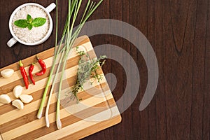 Flat lay cooking image with chopping board, herbs, spices and rice on wooden kitchen table