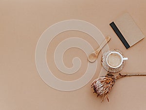 Flat lay with craft notebook, cup of coffee and dry flowers on brown background.