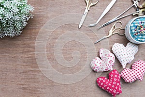Flat lay Crafts made with fabric is a heart shape with sewing tools and accessories on a wooden background