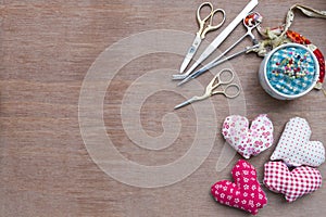 Flat lay Crafts made with fabric is a heart shape with sewing tools and accessories on a wooden background