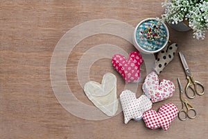 Flat lay Crafts made with fabric is a heart shape with sewing tools and accessories on a wooden background