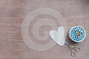 Flat lay Crafts made with fabric is a heart shape with sewing tools and accessories on a wooden background