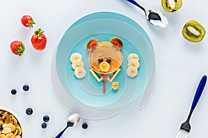 Flat lay with creatively styled children`s breakfast with berries and kiwi