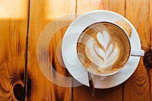 Flat lay. A cup of cappuccino with foam on a wooden table in a light cafe. pattern