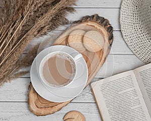 Flat lay with cup of espresso on wooden slice with cookies and book. Top view