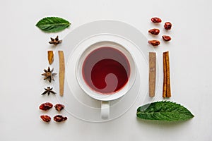 Flat lay a cup of fragrant and tasty herbal or red tea on a white surface and various ingredients