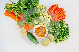 Flat lay of cut fresh vegetables. Healthy carrot, green onion, parsley, lime, garlic, jalapeno against white background. Vegetable