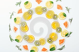 Flat lay with cut fruits and rosemary on white surface.