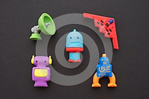 Flat lay of cute AI robots and advance technology eraser toy set on black background minimal style. Kids imagination, learning