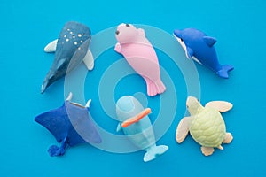 Flat lay of cute aquarium whale, turtle, ray, dolphin, seal toy eraser set on blue background minimal style. Kid learning