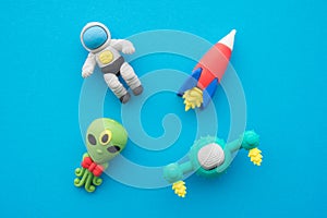 Flat lay of cute astronaut, rocket, alien and ufo outer space eraser toy set on blue background minimal style. Imagination