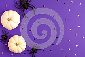 Flat lay of decoration white small Halloween pumpkin template star shapes and black horror spiders on vibrant purple background on