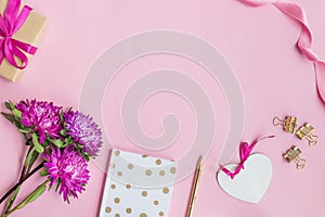 Flat lay desk with pink flowers, notebook and white heart