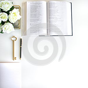 Flat lay with different accessories; flower bouquet, pink roses, open book, Bible