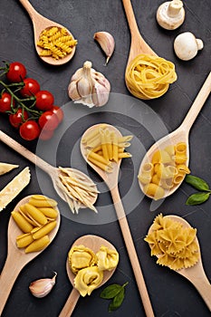 Flat lay with different types of traditional italian pasta. Penne, tagliatelle, fusilli, farfalle, spaghetti and cooking ingredien