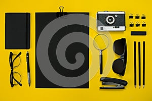 Flat lay display of business office gadgets with notepad, vintage camera, pen, develop, glasses and etc. Top view. Black