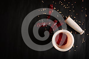 Crushed chili powder in mortar with pestle and red chilies isolated on black background with blank space.