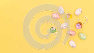 Flat lay easter composition with eggs, eggshell, confetti in trendy colors on yellow backdrop with copy-paste for text