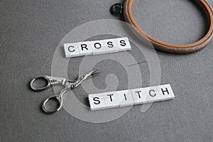 Flat lay embroidery cross on a gray canvas aida