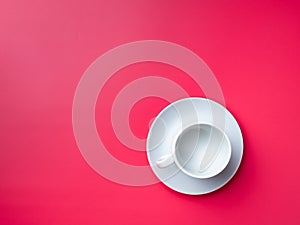 Flat lay. Empty white cup on a saucer on a pink background. Copy space