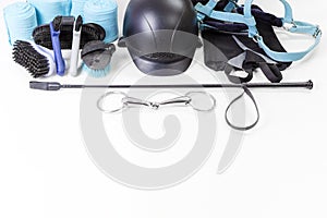 Flat lay of equestrian gear: helmet, brushes, whip, bandages, stirrups, pads, dressage, bridle