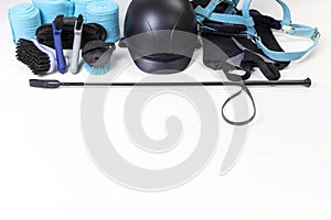 Flat lay of equestrian gear: helmet, brushes, whip, bandages, stirrups, pads, dressage, bridle.