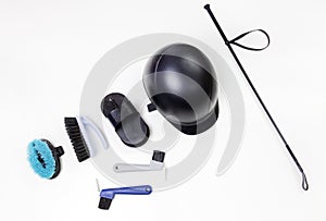 Flat lay of equestrian gear: helmet, brushes, whip, bandages, stirrups, pads, dressage, bridle.