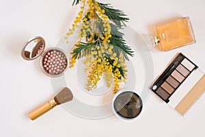 Flat lay fashion blogger. Decorative cosmetics and perfume and a branch of yellow mimosa flowers on a white background