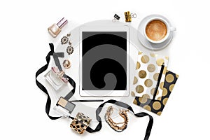 Flat lay fashion feminine home office workspace with tablet, cup of coffee, stylish black gold notebooks, cosmetics and jewelry on