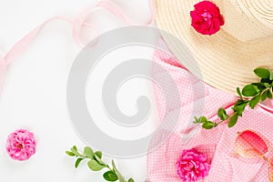 Flat lay fashion office table desk. Female workspace straw hat, rose flower buds, gift box, branches on white background. Top view